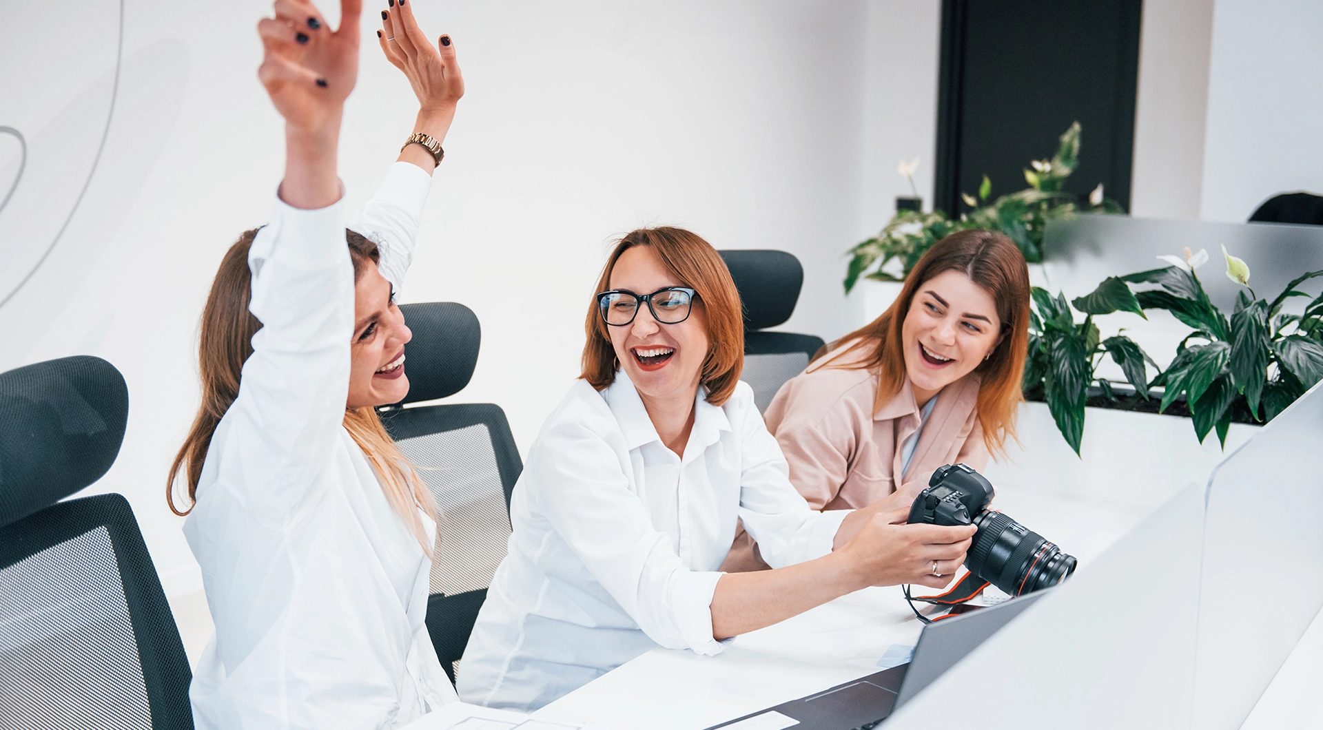 3 creative women sitting at a table laughing and celebrating.