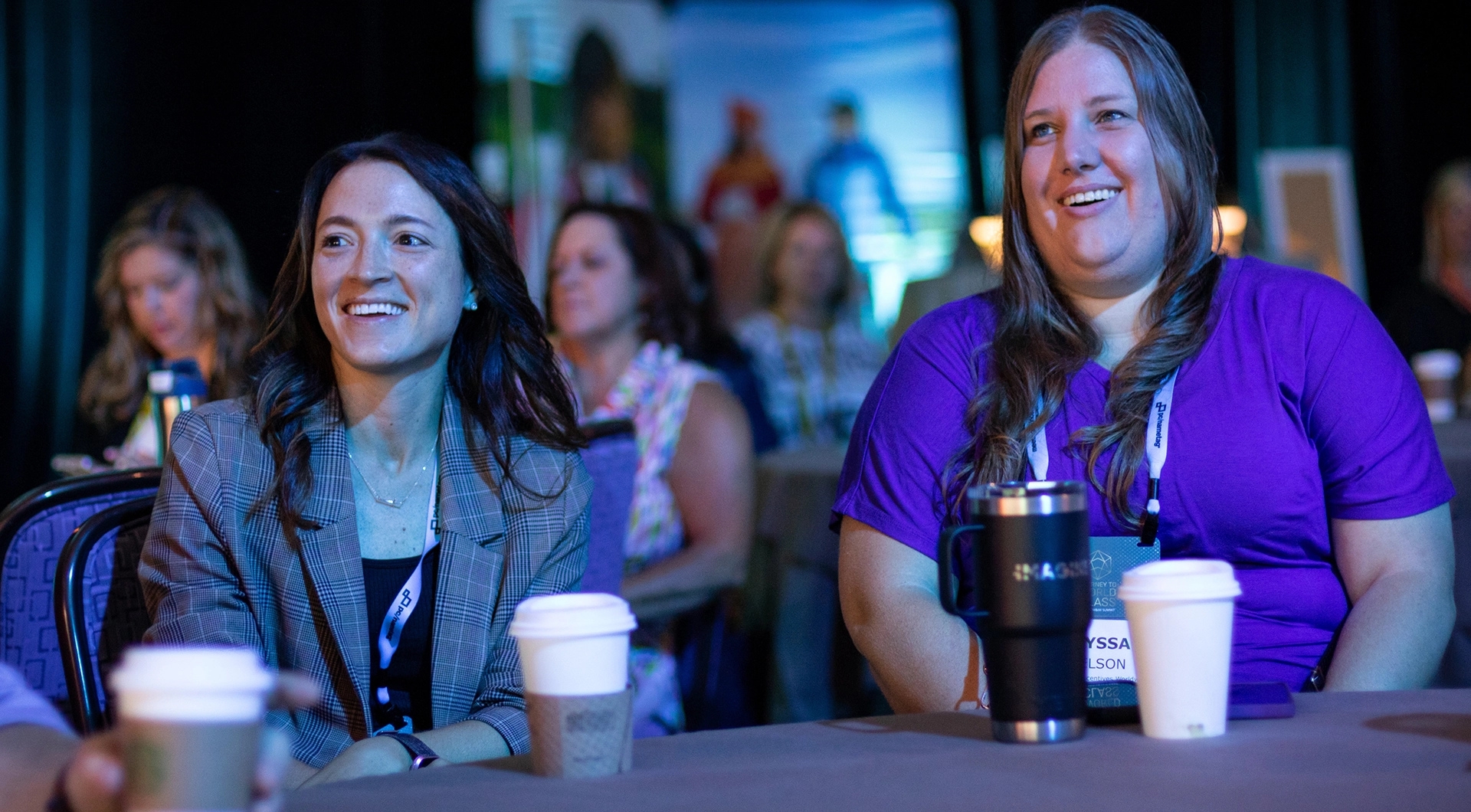 Two attendees watching a speaker.