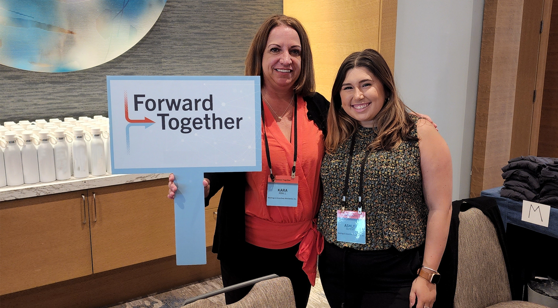 Two M&IW team members holding a branded event sign