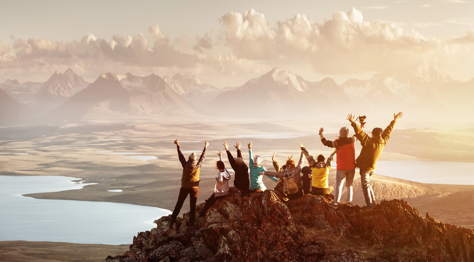 Group of people on top of a mountain celebrating their success of making it to the top.