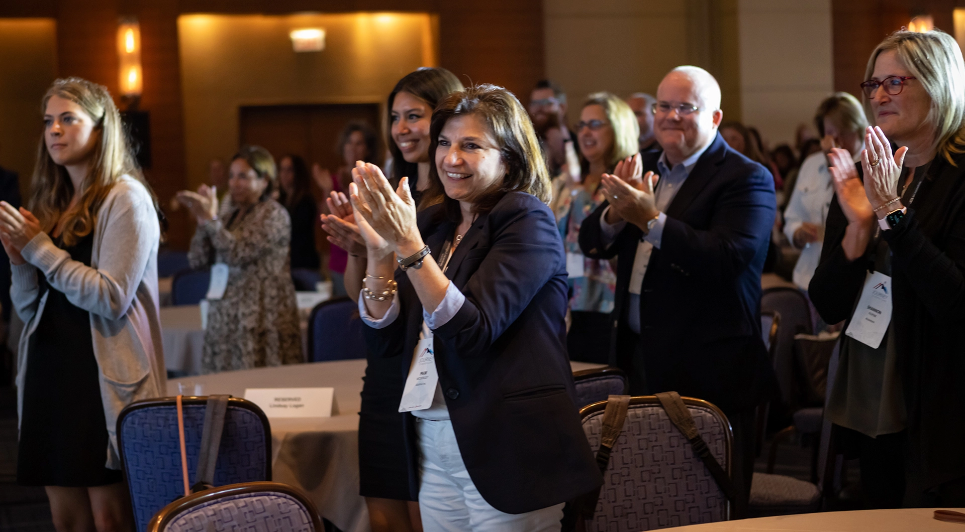 Audience standing and clapping at a corporate event.