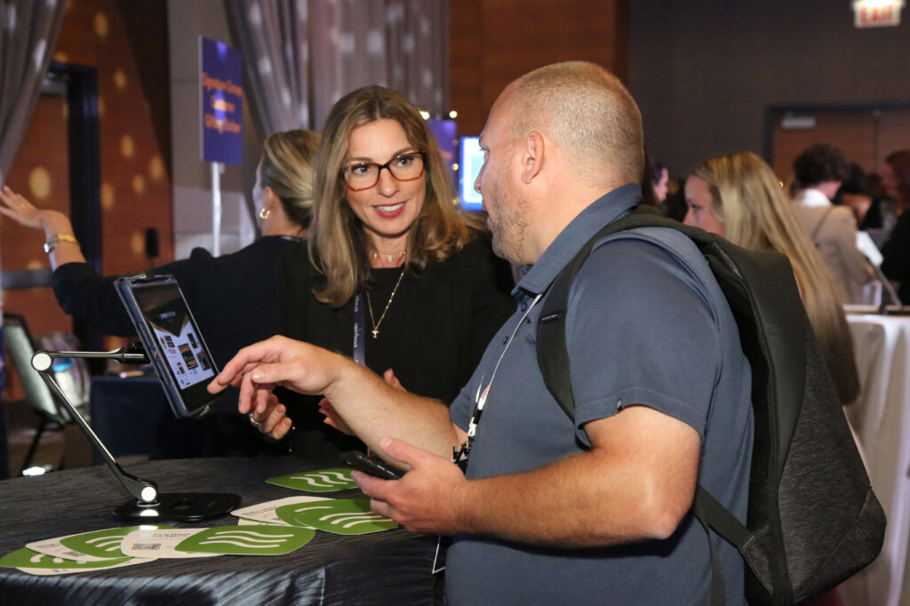 Two attendees using a tablet at the 2024 M&IW Summit