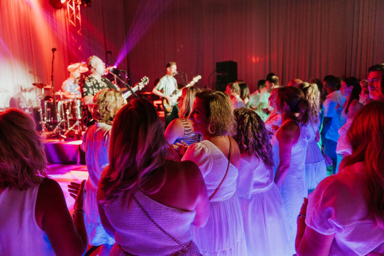 Audience members smiling and dancing while a band plays onstage