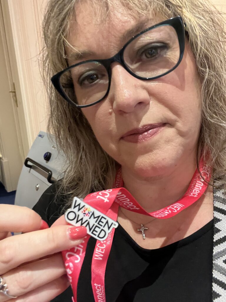 Ella Darby holds her "Women Owned" pin at the 2024 WEConnect International Europe Supplier Diversity & Inclusion Conference