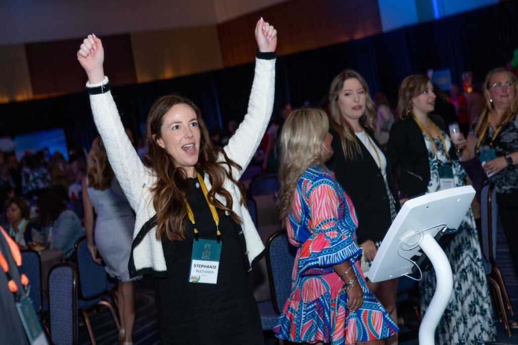 An attendee celebrates with hands raised at the 2023 M&IW Summit