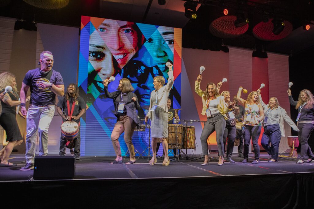 Attendees dancing onstage with maracas during the closing session of the 2025 M&IW Summit